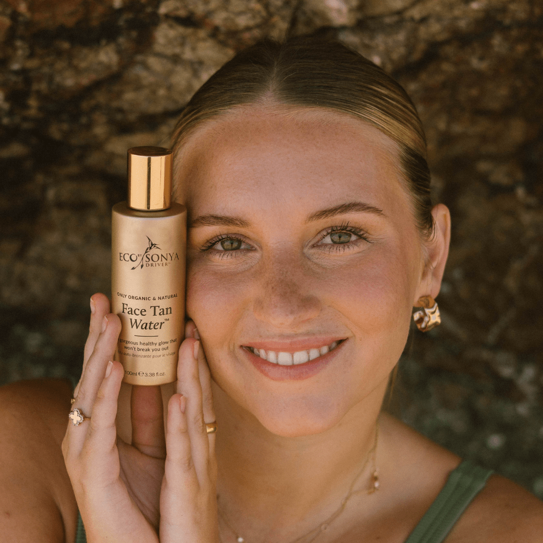Woman holding Eco By Sonya Face Tan Water bottle near her face, organic natural Australian made sunless tanner.